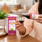 Woman pouring a dose of Gyan Hem Sakhi Ayurvedic Syrup into a measuring cup.